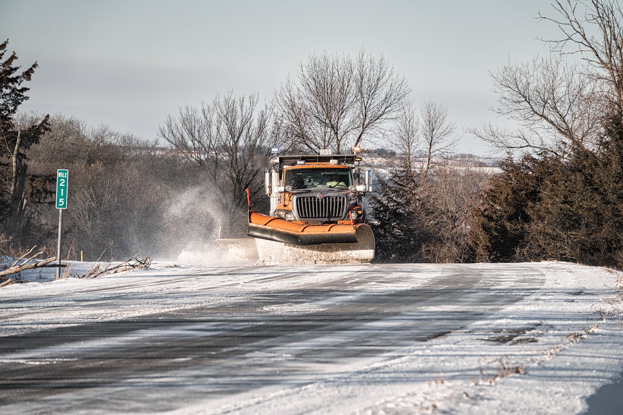 A snowplow clears a rural road in winter, showcasing winter maintenance.