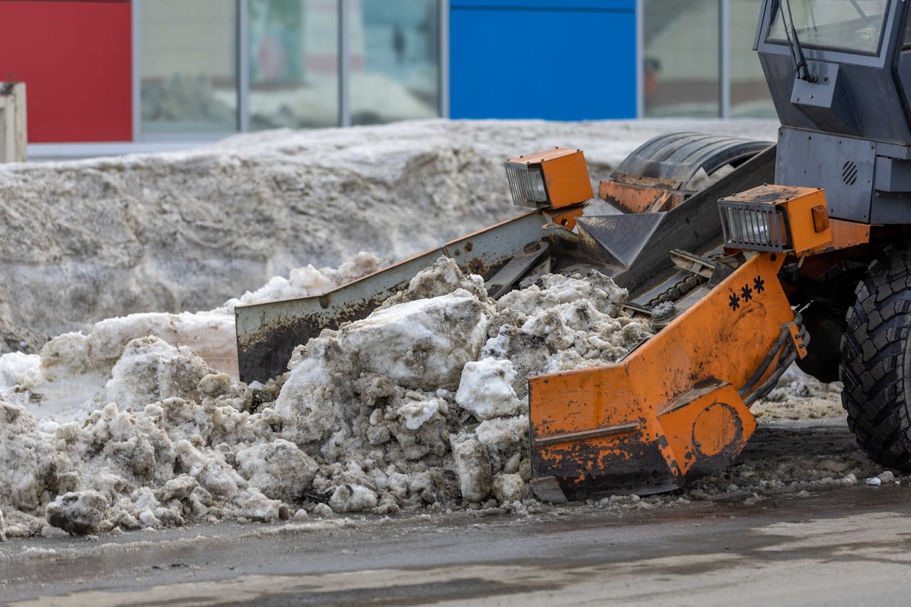 Heavy bulldozer clearing snow from urban area, showcasing powerful industrial machinery in action.